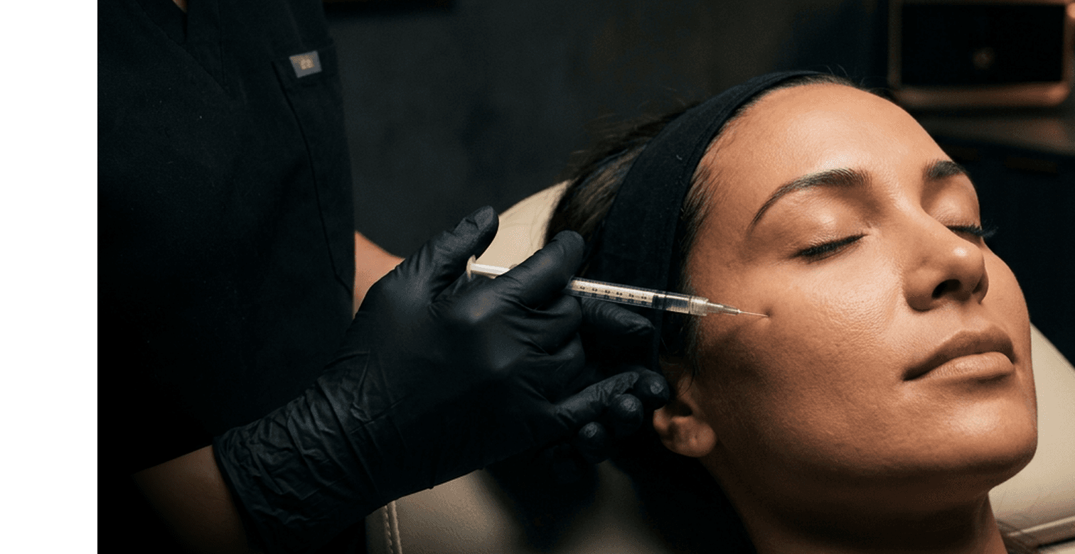 A patient receiving a Botox injection near the brow in a dimly lit treatment room